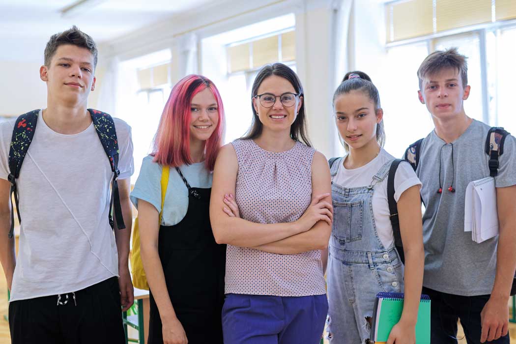 Young people with their tutor in a classroom looking at the camera