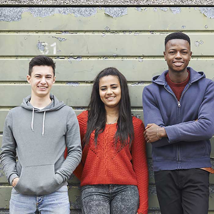 Young people looking happy stood against a wall
